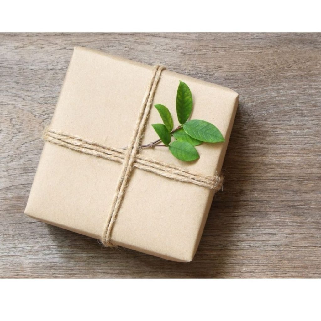 Verpacktes Geschenk mit Kordel und Olivenzweig auf Holz
