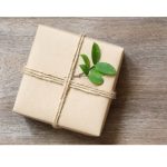 Verpacktes Geschenk mit Kordel und Olivenzweig auf Holz