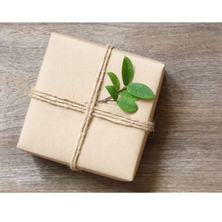 Verpacktes Geschenk mit Kordel und Olivenzweig auf Holz