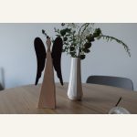 Zwei Holzengel mit dunklen Flügeln neben einer Vase