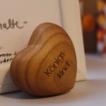 Holzherz mit Gravur „Königskind“ neben einer Karte