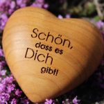 Holzherz mit Gravur „Schön, dass es Dich gibt“ vor blühendem Heidekraut
