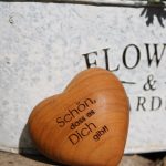 Holzherz mit Gravur „Schön, dass es Dich gibt“ vor einer hellen Wand
