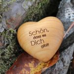 Holzherz mit Gravur „Schön, dass es Dich gibt“ auf einem Baumstamm mit Herbstlaub