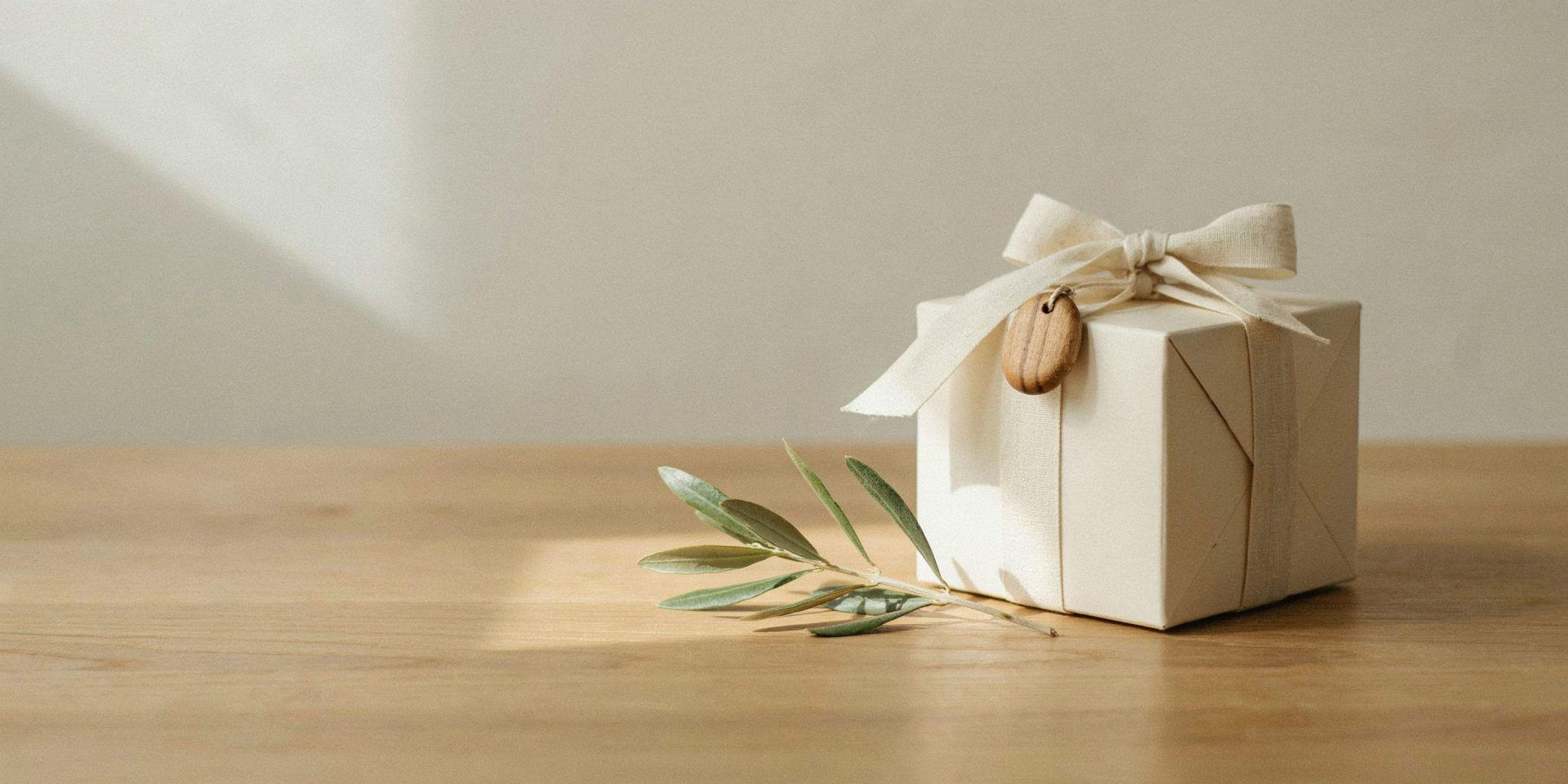 Cremefarbene Geschenkbox mit Leinenband und Olivenholz-Anhänger